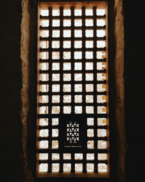 a window in a stone wall with light coming through it