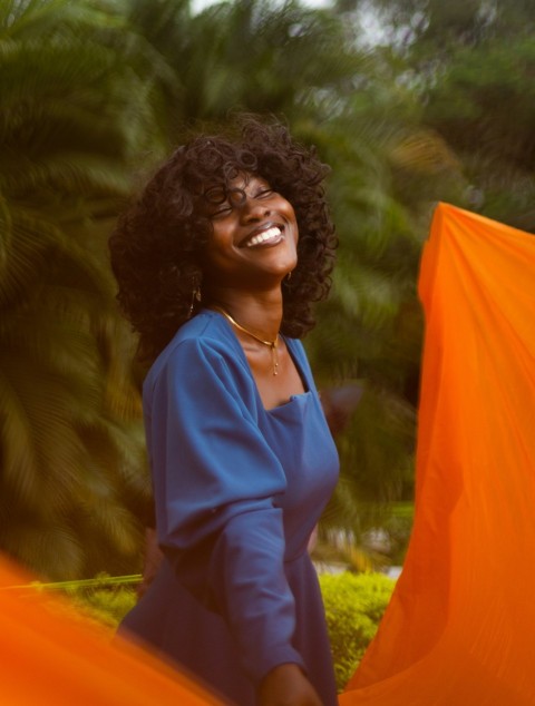 a woman smiling and holding an orange cloth