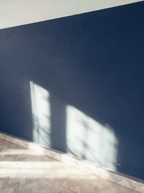 a room with a blue wall and two windows