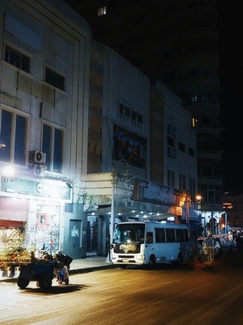 a city street at night with a bus parked on the side of the street