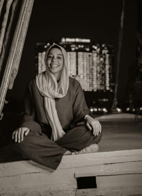 a woman sitting on a ledge in front of a cityscape