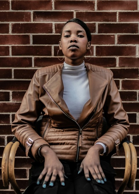 a woman sitting in a chair in front of a brick wall