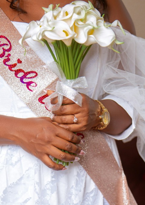 a woman wearing a sash holding a bouquet of flowers