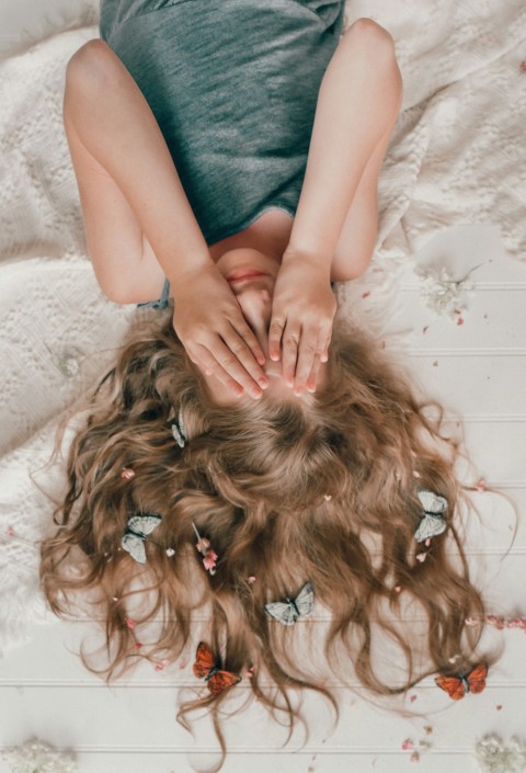 a woman laying on top of a white bed owlOF