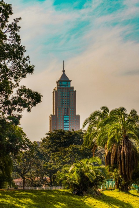 brown concrete building near green trees under blue sky during daytime