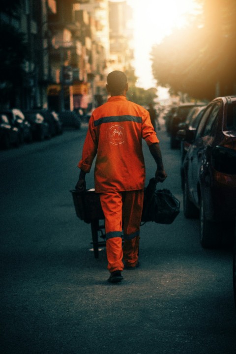 a man in an orange coverall walking down a street