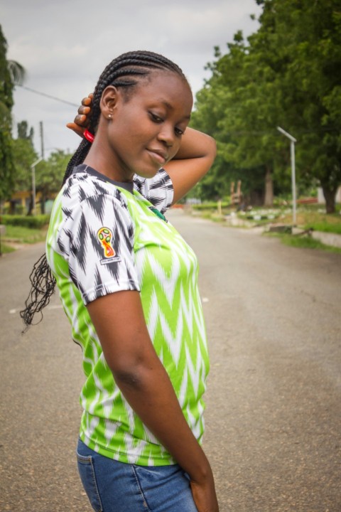 girl in green and white stripe shirt standing on road during daytime