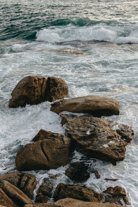 a person standing on top of a rock next to the ocean