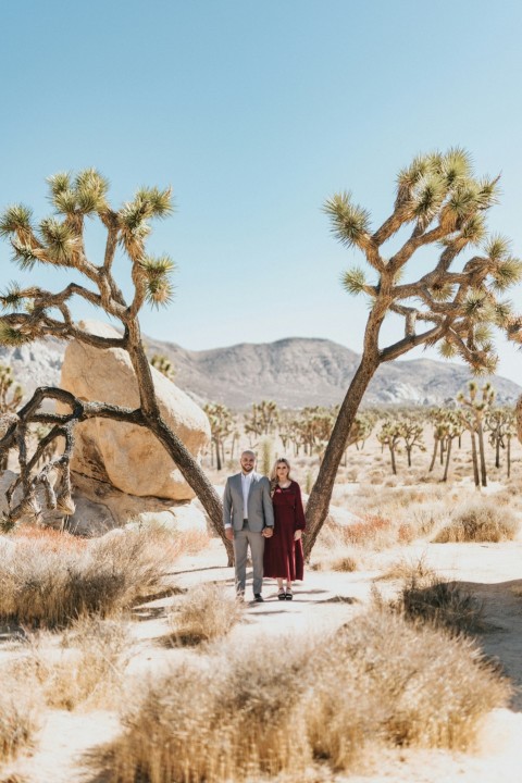 man and woman standing near brown rock formation during daytime