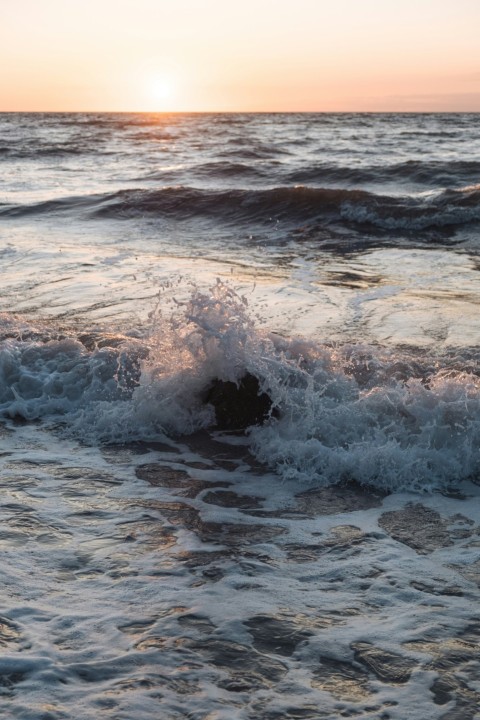 the sun is setting over the ocean waves