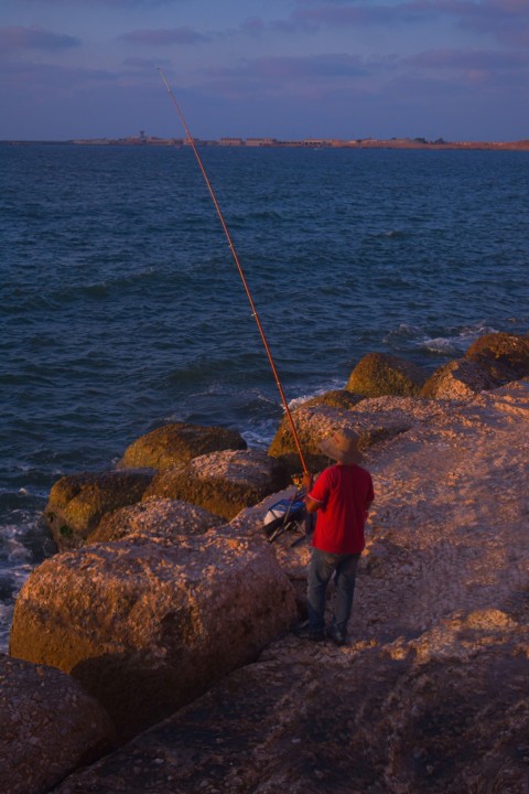 a man standing on a rock next to a body of water