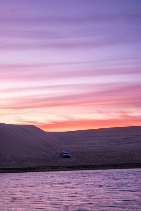 a truck is parked on the shore of a body of water