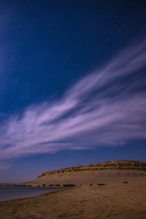 the night sky is lit up over a sandy beach