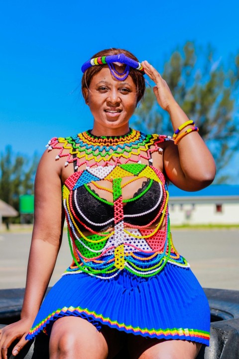 a woman in a colorful dress sitting on a tire aY32lX_B