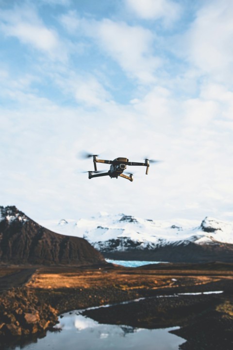 black quadcopter drone over body of water