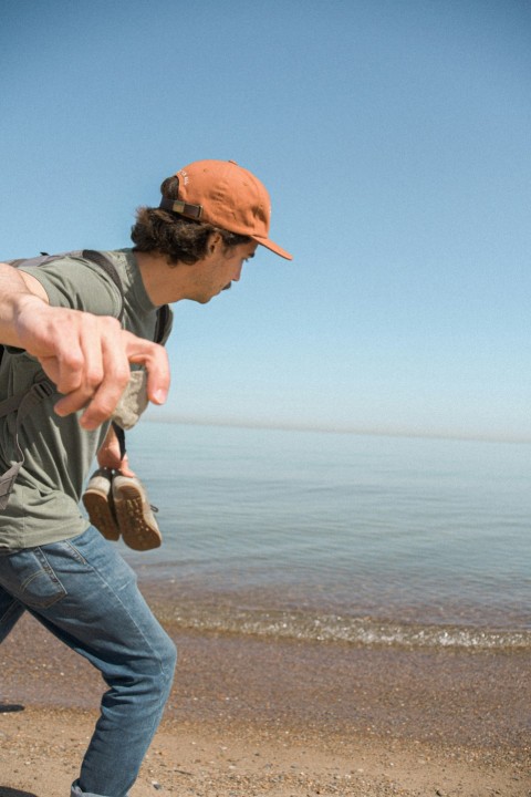 man in gray shirt and blue denim jeans holding brown leather boots