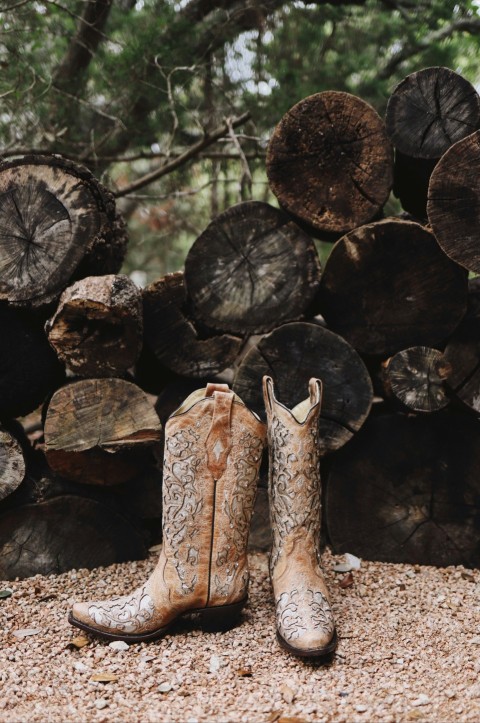 pair of brown leather cowboy boots near cut logs