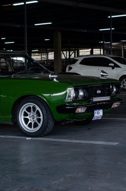 a green car parked in a parking lot next to a white car