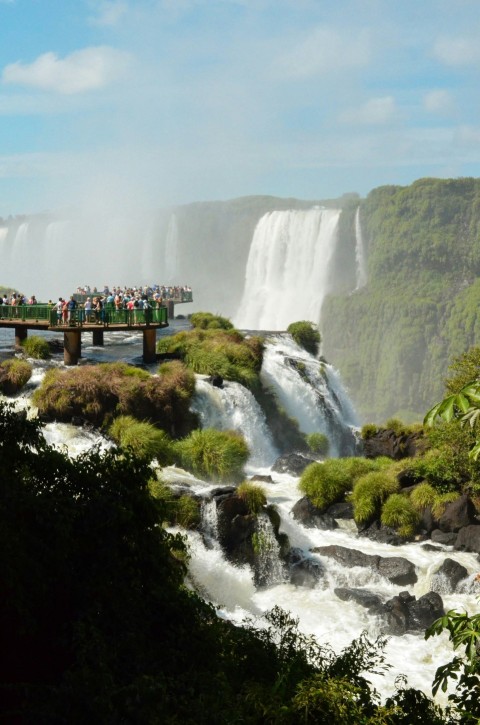 people standing on wooden bridge over waterfalls during daytime