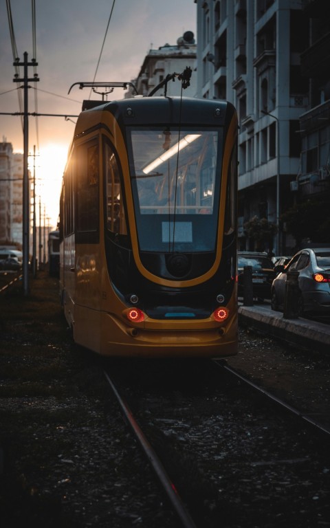 a yellow train traveling down train tracks next to tall buildings