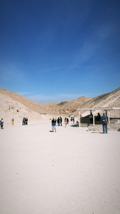 a group of people standing on top of a sandy beach