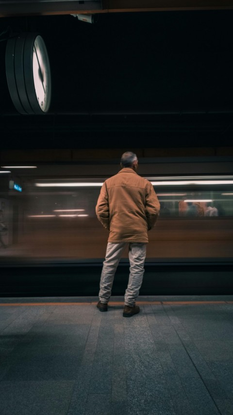 a man standing in front of a train at a train station hXgz