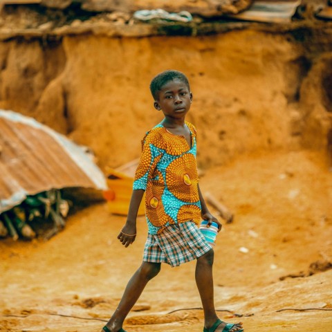 a young boy walking across a dirt field LSBa84C2